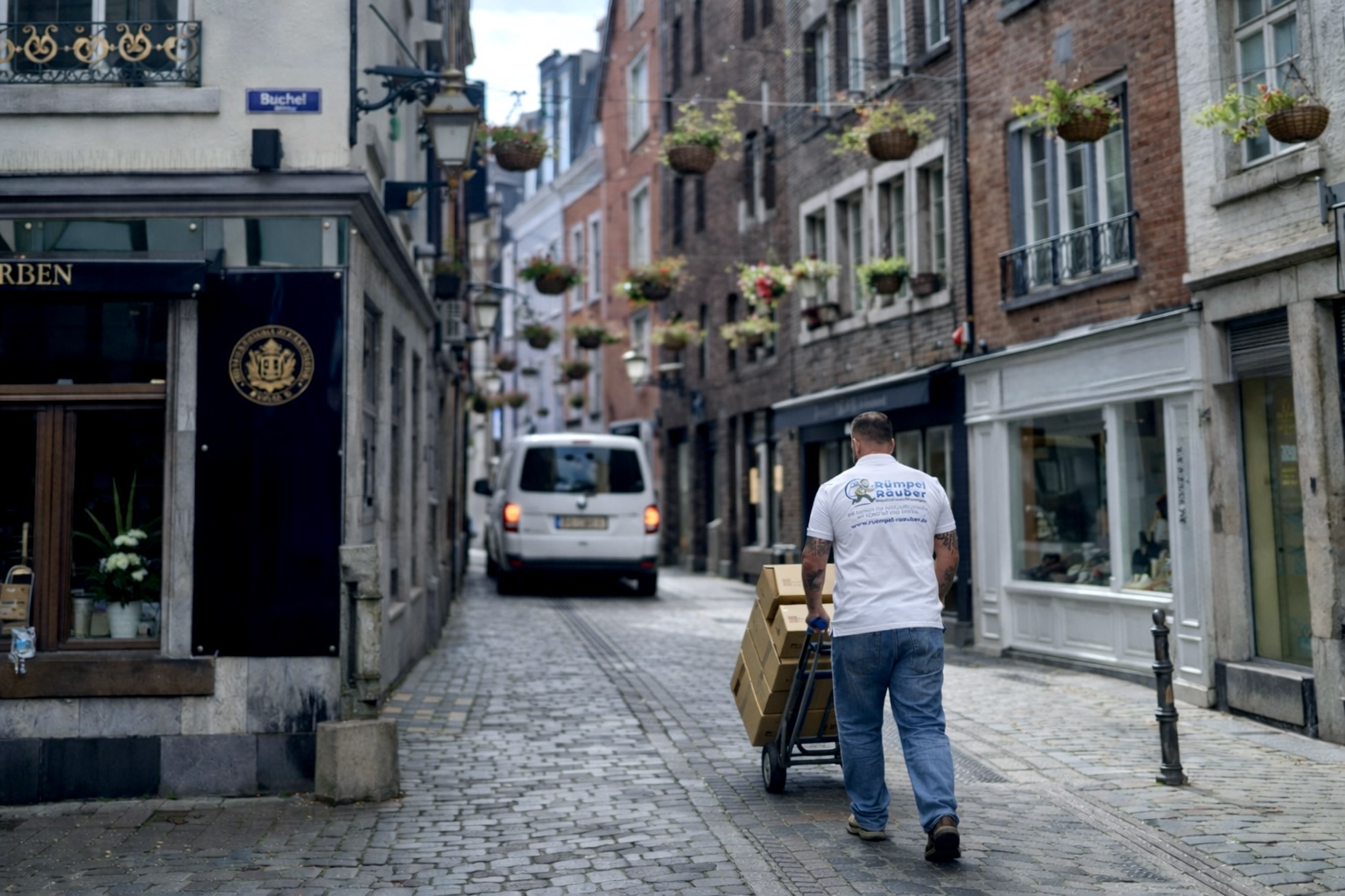 Patrick schiebt in Aachener Gasse mit einem Sackkarren Pakete zu seinem Transporter