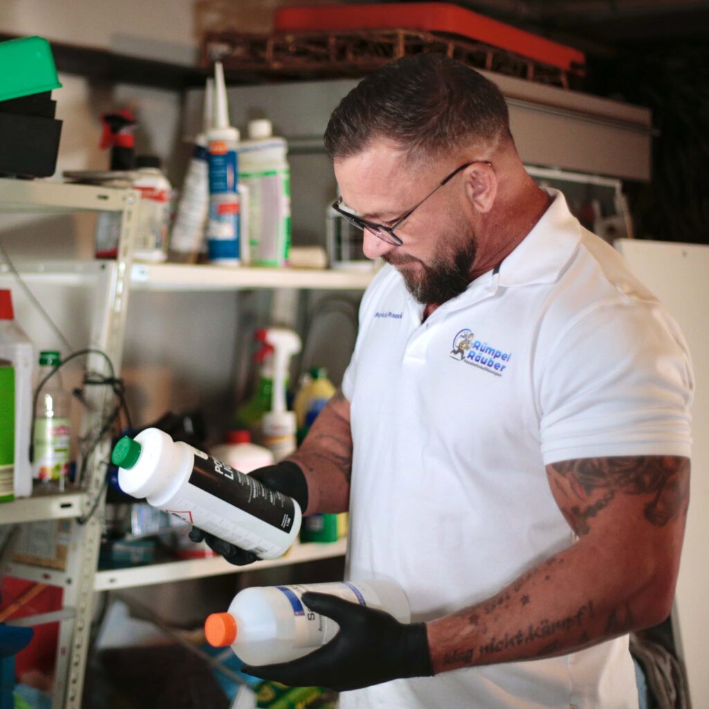 Person bei einer Entr&uuml;mpelung in Aachen, die zwei Gefahrenstoffflaschen vergleicht
