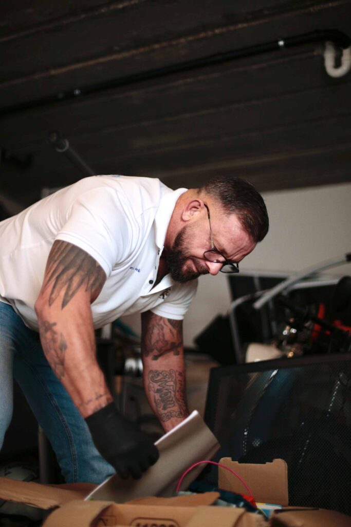 Mann packt Sachen in eine Karton bei einer Entr&uuml;mpelung in einer Garage