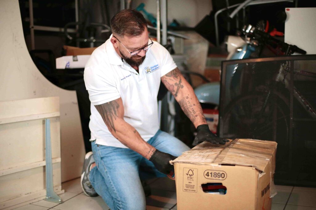 Mann schlie&szlig;t und verpackt Karton in einer zu entr&uuml;mpelnden Garage.