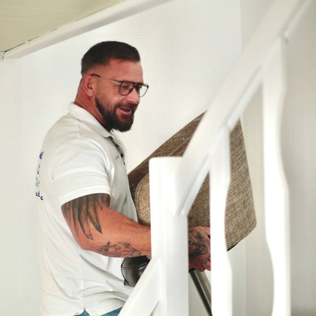 Person die bei einer Entr&uuml;mpelung in Aachen einen Stuhl eine Treppe hochtr&auml;gt