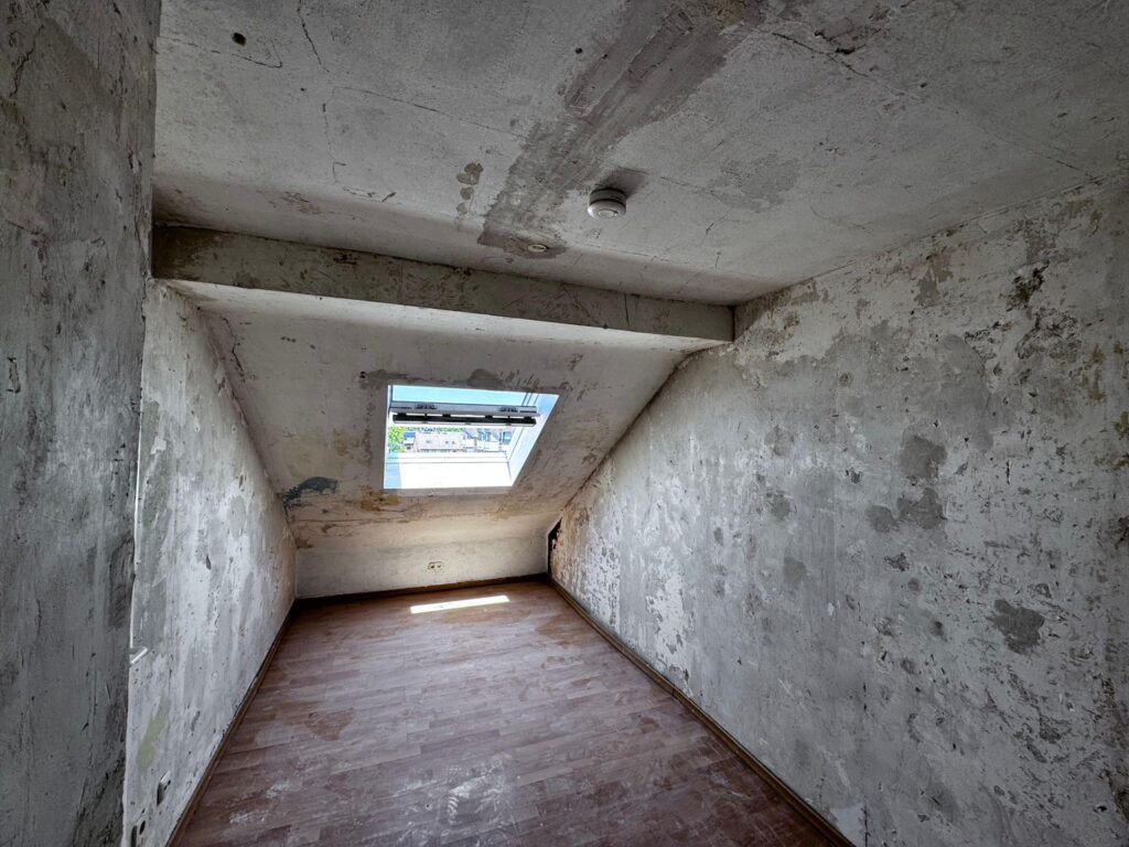 Leerer Raum mit enfernter Tapete mit schr&auml;gem Fenster