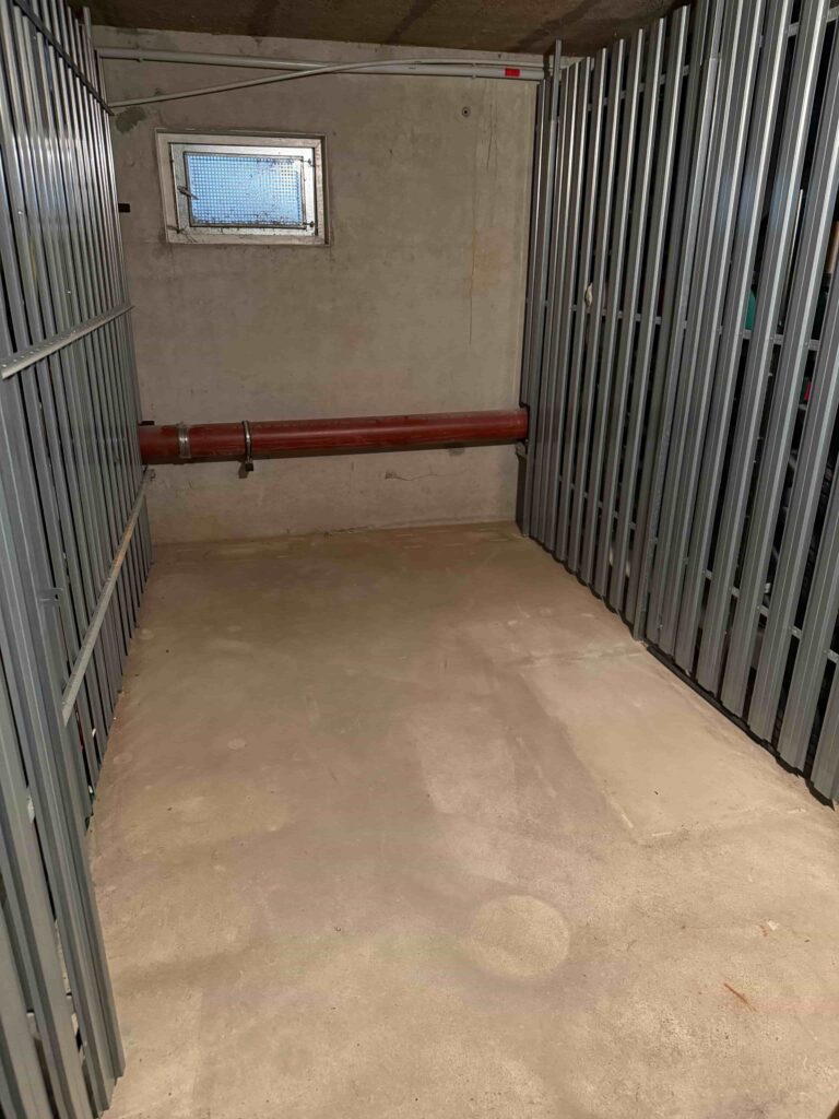 Leerer Kellerraum mit Metallgittern.