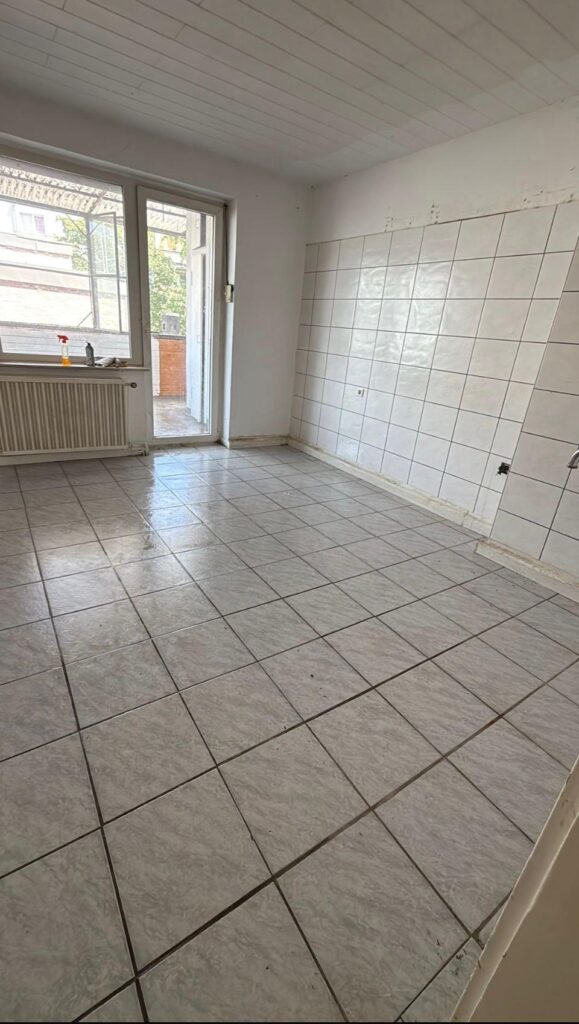 Leere, geflieste K&uuml;che mit Fenster einer Messientr&uuml;mpelung